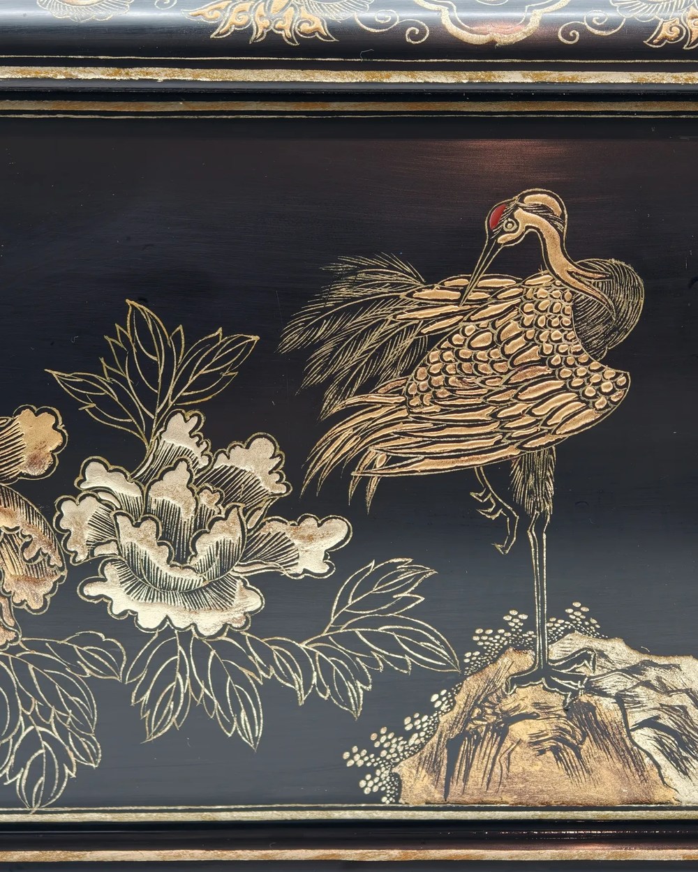 Close view of a lacquer urn body showing layered gold-line decoration across a deep black ground